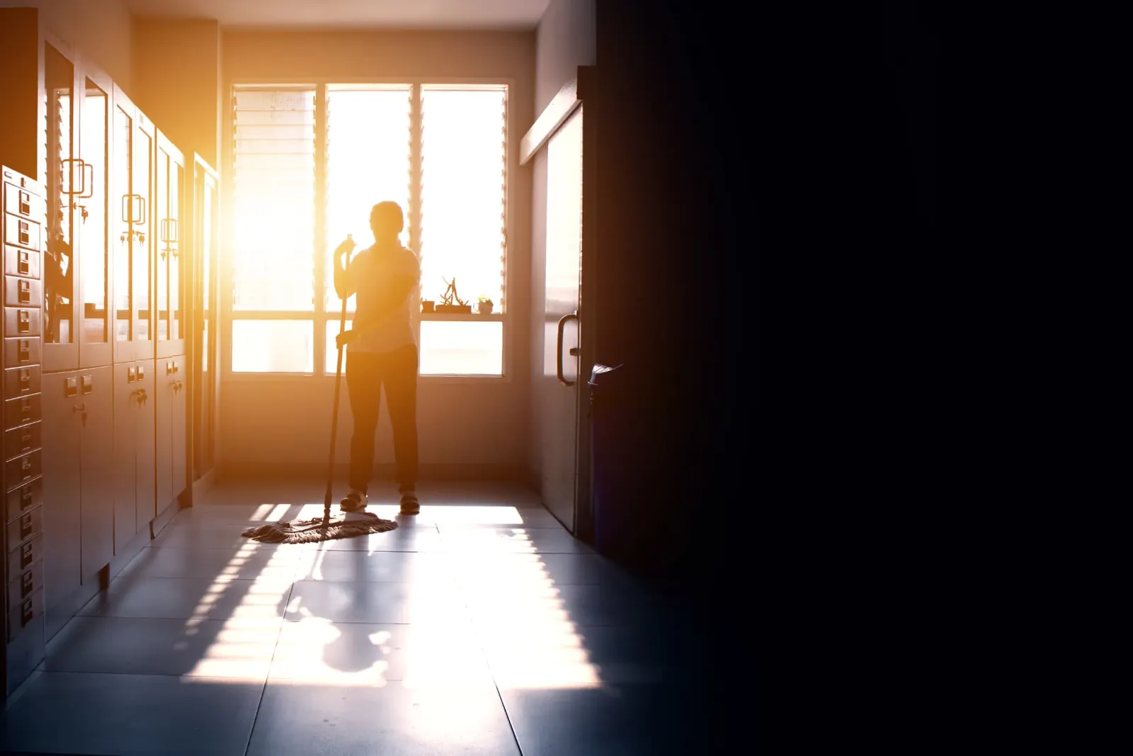 Préposé à l'entretien lavant un corridor en fin de journée