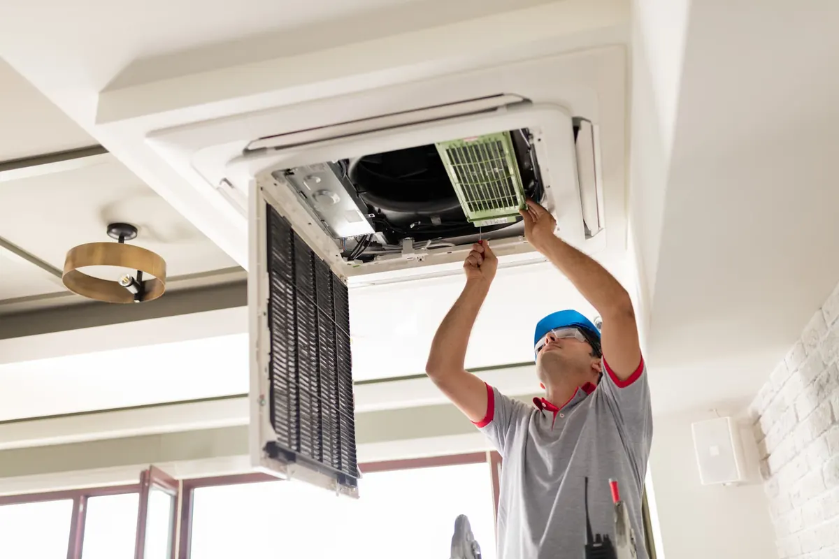 Technicien entretenant une unité de ventilation au plafond